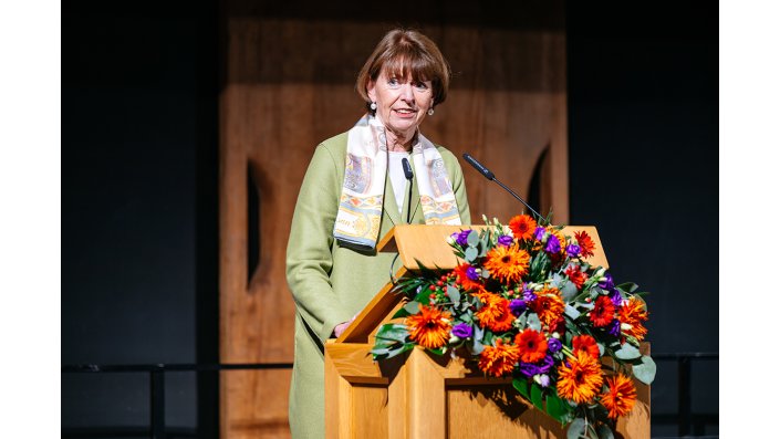 Kölns Oberbürgermeisterin Henriette Reker steht an einem Rednerpult und spricht zum Publikum.