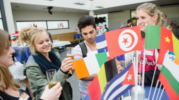 Am Stehtisch mit ausländischen Flaggen genießen Studenten ihr Kölsch. (Bild: Costa Belibasakis / FH Köln)