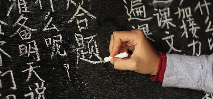 Person schreibt chinesische Zeichen auf eine Tafel (Image: f.ield_of_vision/iStock.com)